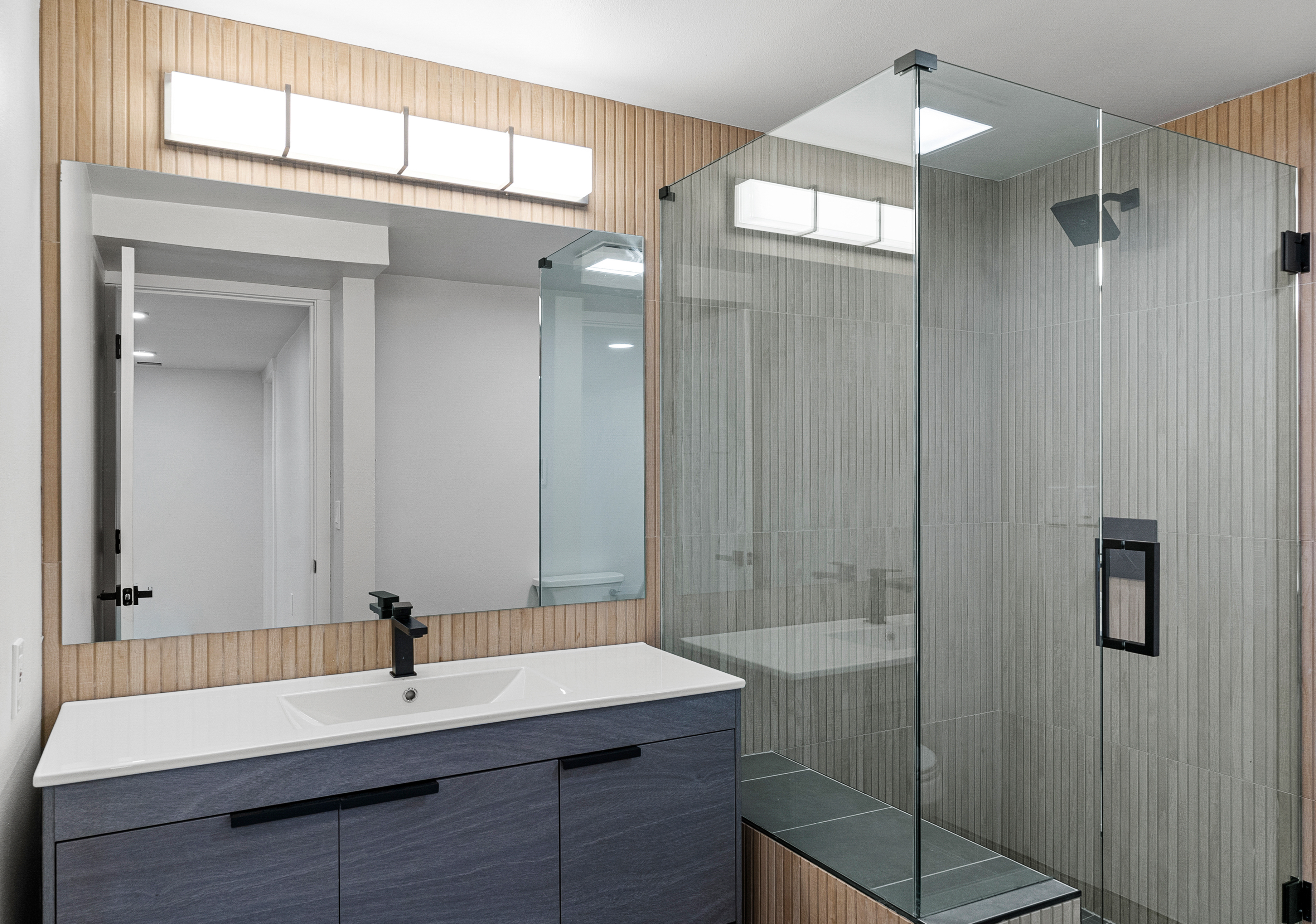 Walk-in glass shower with wood-slat accent wall